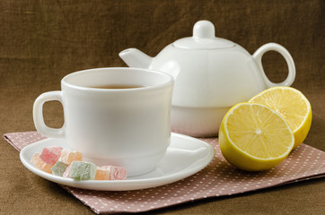 on napkin cup of tea with lemon in saucer and teapot