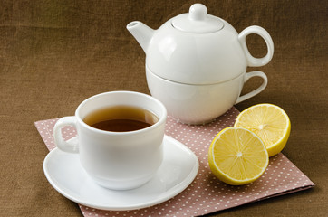 on napkin cup of tea with lemon in saucer and teapot