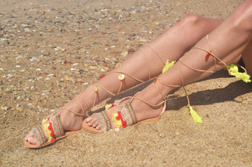 model advertises bohemian greek sandals at the beach - summer shoes advertisement