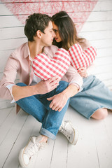 Fototapeta premium Young couple with heart-shaped pillows posing for love-story in