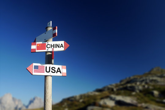 USA and Chinese flags on mountain signpost.