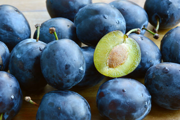 Many fresh Plums or Zwetschge and cut can see the seed on wooden floor.