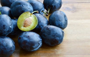 Many fresh Plums or Zwetschge and cut can see the seed on wooden floor.