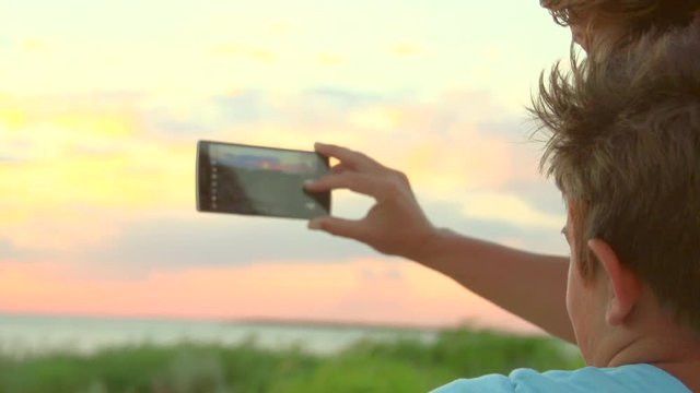 Mother with her son taking picture with smartphone outdoors. Vacation concept. Slow motion 240 fps, high speed camera. Full HD 1080p
