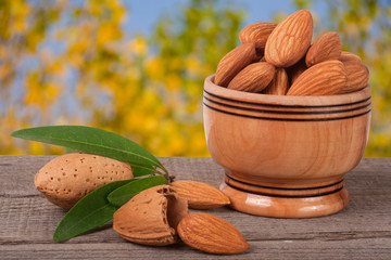 almonds in a bowl on the old wooden board with blurred garden background
