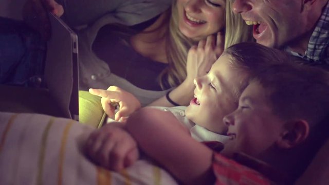 Happy family watching movie on tablet pc in a dark room. Full HD 1080p, slow motion 240 fps