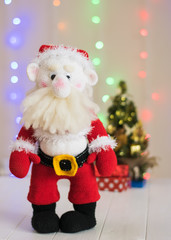 Knitted toy Santa Claus on a background of colorful bokeh.