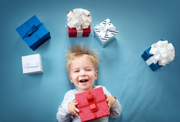 Smiling baby on red blanket with presents