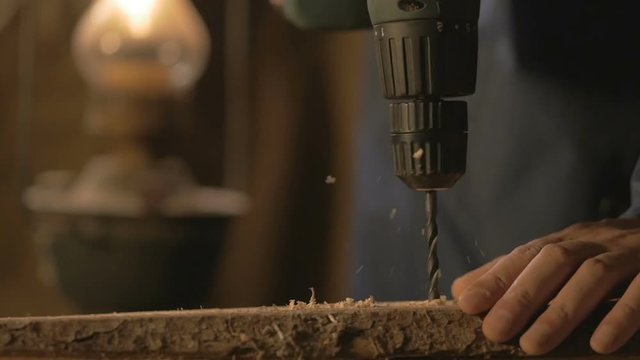 The carpenter makes a hole in the Board drill. master works in the Studio tool.