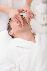 Obraz na płótnie Canvas Masseuse massaging male face at spa