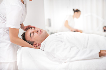 Fototapeta na wymiar Skillful masseuse massaging male head
