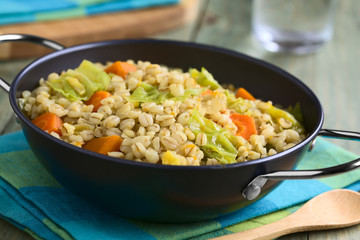 Vegan stew made of wheat grains, savoy cabbage, carrot, pumpkin and onion, photographed with natural light (Selective Focus, Focus one third into the dish)
