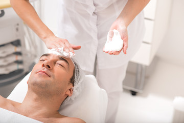 Obraz na płótnie Canvas Senior male client getting facial skin treatment