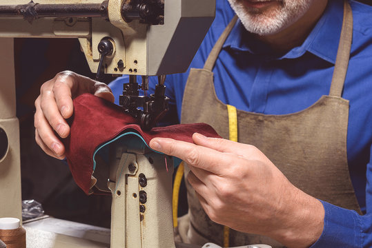 Shoemaker In Apron Sews Shoes