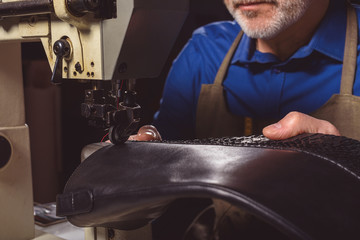 artisan sews leather shoes indoors