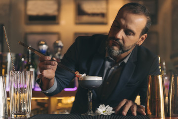 Barman is making cocktail at night club.