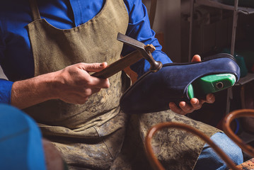 artisan holding a boot and hammer