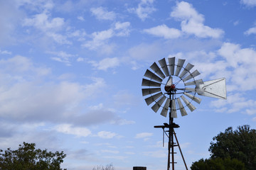 Closeup on upper portion of Vintage Wind Mill in Central California against partly cloudy sky