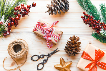 Christmas decoration with fir tree branch, pine cones, scissors and gifts on wooden background, top view, flat lay.