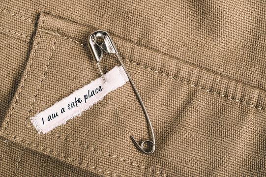 Safety pins on clothes with label "I am a safe place" as a symbol of solidarity