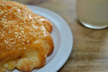 Closeup on Austrian pastry filled with seasonal fruit, covered with almond crumbs and coated with sugar, on white plate over wooden background, viewed from above at an angle, with glass of milk