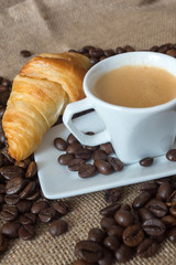 Cup and grain of coffee over textile background