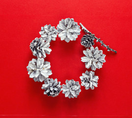 Round frame of white pine cones on a red background. Christmas b