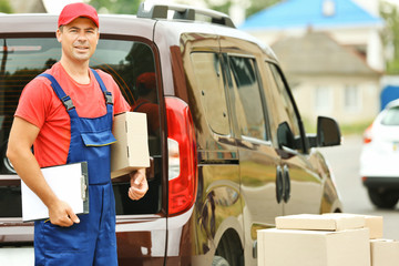 Delivery concept. Postman with parcels near a car