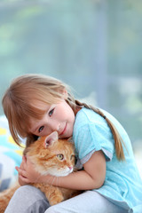 Cute little girl with red cat on window background