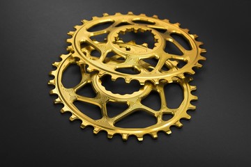 Golden oval bicycle chainring at grey background