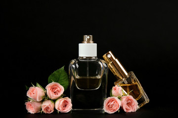 Perfume bottles with flowers on black background