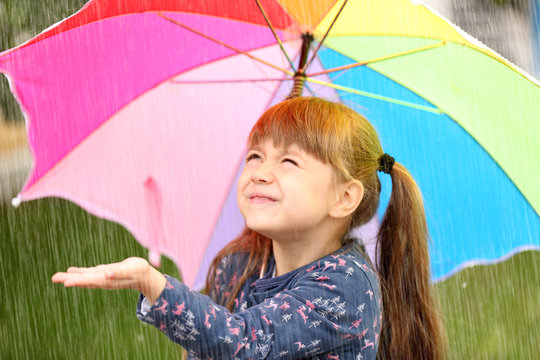 Portrait of cute girl with umbrella in rain