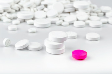 Bunch of white tablets. Scattered pills. Single pink pill