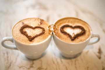 wedding rings and two cups of coffee with foam in the form of heart. Wooden background. - 126872519