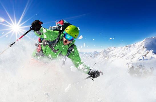 Freeride skier on piste running downhill