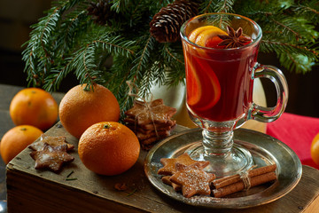 Mulled wine with cinnamon sticks, tangerine, ginger cookies and spruce branches