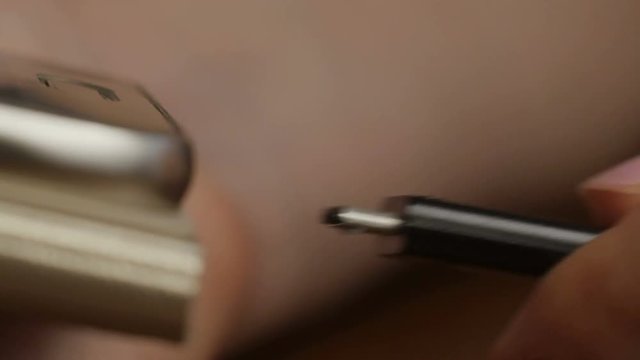 closeup of the hands of a man plugging in the plug of his smpartphone in a socket, with a filter effect