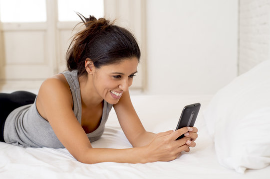 hispanic woman relaxed using internet mobile phone sending message at home bedroom smiling happy