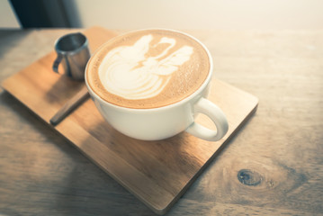Latte coffee cup on wooden table in the morning with sunlight