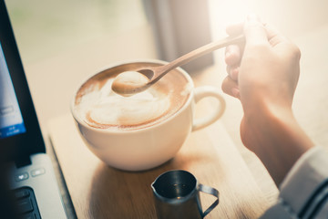Latte coffee cup on working table in the morning with sunlight