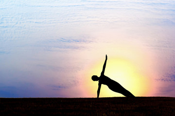 Silhouette of woman at sunset. Yoga, fitness and healthy lifestye