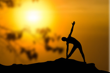 Silhouette of woman practicing yoga at sunrise