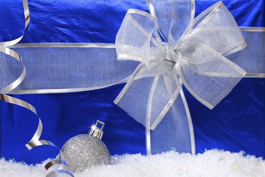 Gift in the blue box and silver Christmas ball. Close-up