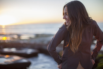 Portrait of a beautiful woman standing on the rocky edge of a San Diego beach at sunset.  California.