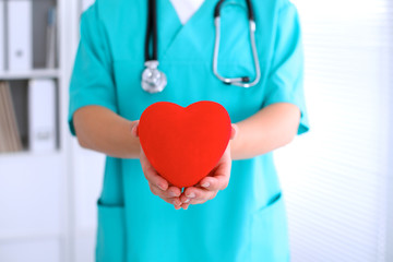 Female surgeon doctor with stethoscope holding heart.