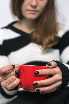 girl holding a red cup of tea