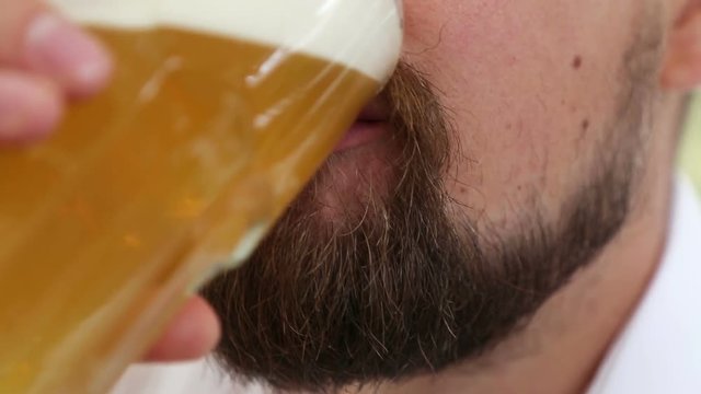 Man with foam on nose and moustache drinking beer