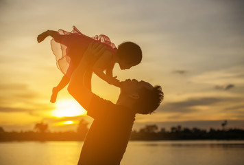 Father took the baby learn to walk at sunset.
