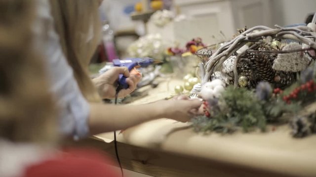 girl in the studio preparing decorations for Christmas wreaths
