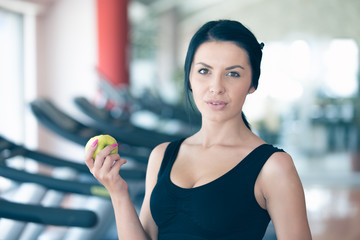 Torso of a woman with a green apple on a dark background